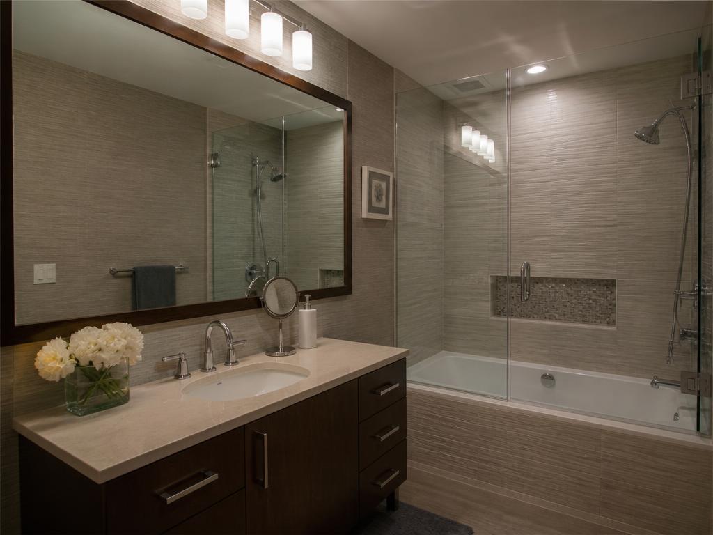 Custom-cut framed mirror and glass tub enclosure in a remodeled bathroom
